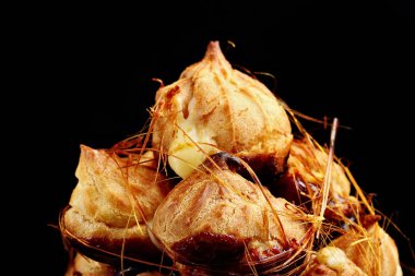 Siyah arka plan üzerine karamel ile pasta profiterol. Closeup.Selective odak