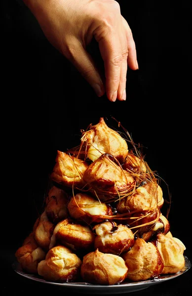 Taart profiterollen met karamel op zwarte achtergrond. Selectieve aandacht — Stockfoto