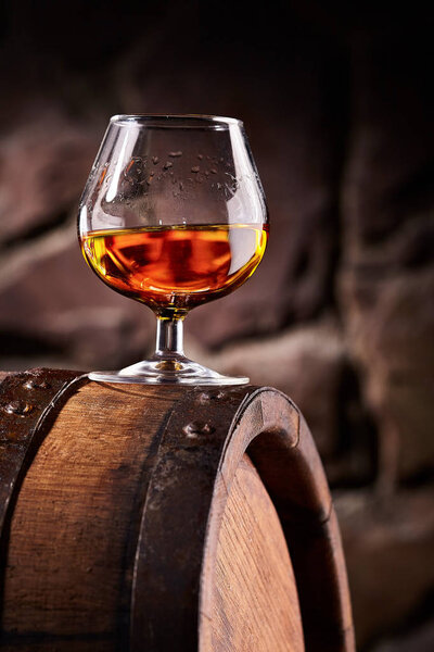 Стакан коньяка на старой деревянной бочке
