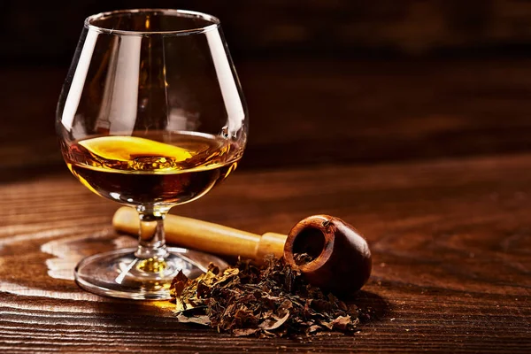 Verre de cognac et pipe avec tabac sur table en bois — Photo
