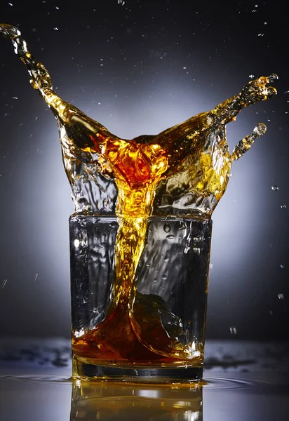 Skvätt whiskey med is. Grå bakgrund. Begreppet alkohol splash — Stockfoto