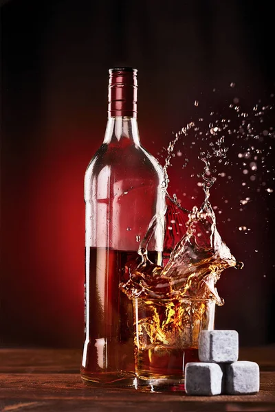 Whiskey flaska med glas stänk över isen stenarna för whisky . — Stockfoto