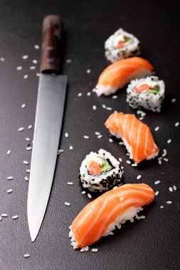 Suşi nigiri sushimi'si suşi bıçak ile somon ve rulo suşi philadelhia ile. Taş arka plan üzerinde. Uzay kopyalayın. Sushi menüsü. Japon yemekleri.
