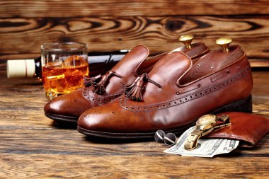 Kahverengi brogues. Erkekler accessroies, altın izle, deri potmone cüzdan para ile. Şişe ve glas viski defocused. Kopya alanı