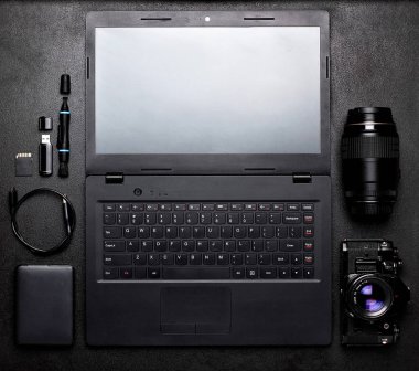 Dizüstü bilgisayar, kameralar, lensler, içme sabit diskler, usb flash. Yaratıcı tasarımcı veya fotoğrafçı teknoloji trendleri kavramı ile siyah masada çalışma alanı.
