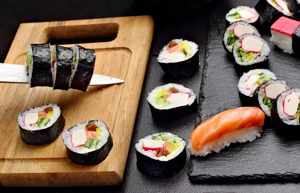 Sushi Cuting Sulla tavola di legno. Vicino a serie di sushi su asse di pietra.Makki — Foto Stock