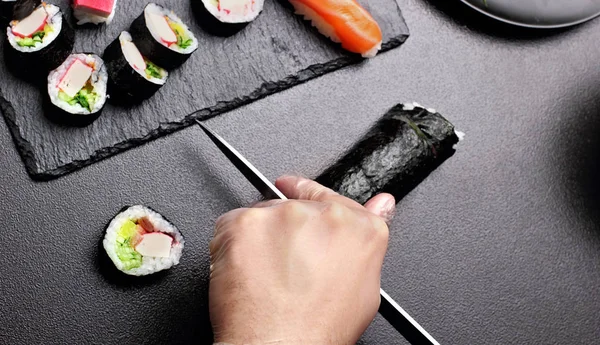 Knife in hand cuts the roll closeup on a stone board.copy space.top view — Stock Photo, Image