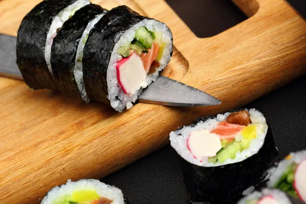 Sushi rolls makki with crab sticks on knife .Closeup. Macro view — Stock Photo, Image