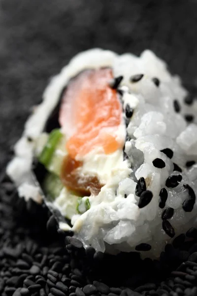 Japanese sushi roll philadelphia on black sesame. Selective focus. Blurred foreground and background. Macro view — Stock Photo, Image