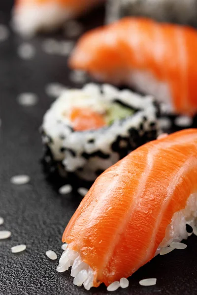 Nigiri sushi z łososiem na czarnym tle kamienia. Philadelphia rolka rozmytym — Zdjęcie stockowe