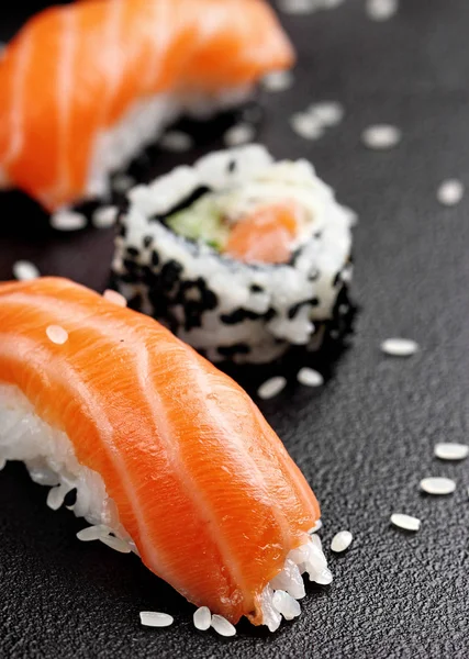 Nigiri sushi z łososiem na czarnym tle kamienia. Philadelphia rolka rozmytym — Zdjęcie stockowe