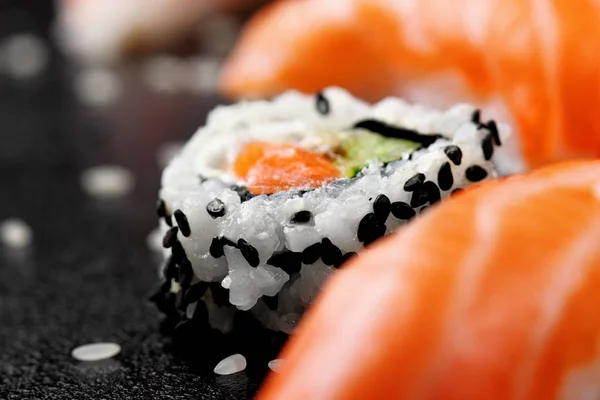 Японский суши-ролл на черном кунжуте. Выборочный фокус. Размытый лосось нигири на переднем плане и заднем плане. Макровзгляд — стоковое фото