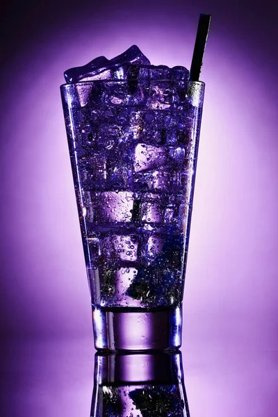 Cocktail con gin e limone con ghiaccio su fondo viola . — Foto Stock