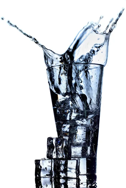 Agua en vidrio que se extiende aislada sobre fondo blanco — Foto de Stock