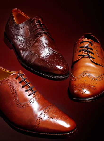 Fashion classical polished men 's brown oxford brogues shades of brown oxford brogues.Conept flying shoes.Closeup.Red background — стоковое фото