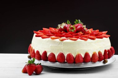 Vanilyalı krema ile Çilekli pasta. Siyah arka plan.