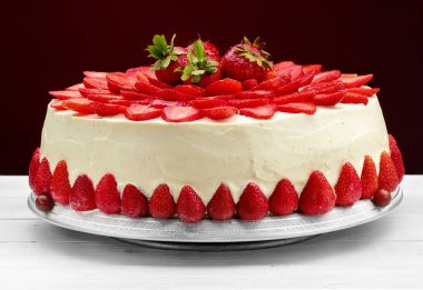 Vanilyalı krema ile Çilekli pasta. Kırmızı bir arka plan beyaz ahşap masa