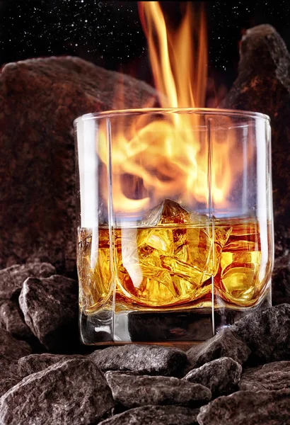 Glass of whiskey with fire and and ice inside.Creative photo glass of whiskey in stone mountain with fog.Copy space.Advertising shot — Stock Photo, Image