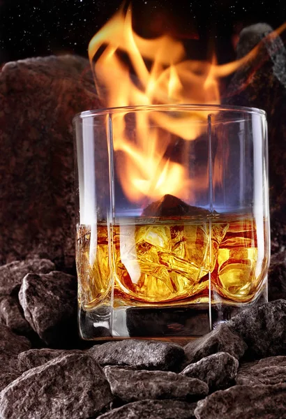Glas whiskey met vuur en en ijs binnen. Creatieve foto glas whiskey in stone mountain met mist. Kopieer ruimte. Schot reclame — Stockfoto