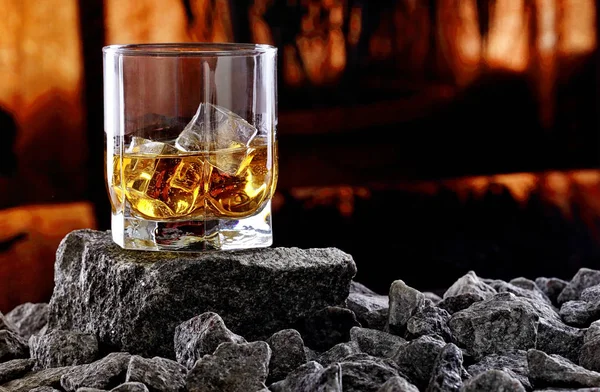 Vaso de whisky y hielo. Foto creativa vaso de whisky en piedra con fondo al atardecer. Espacio de copia. —  Fotos de Stock