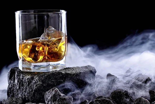 Glas whiskey en ijs. Creatieve foto glas whisky op steen met mist. Kopieer ruimte. Schot reclame — Stockfoto