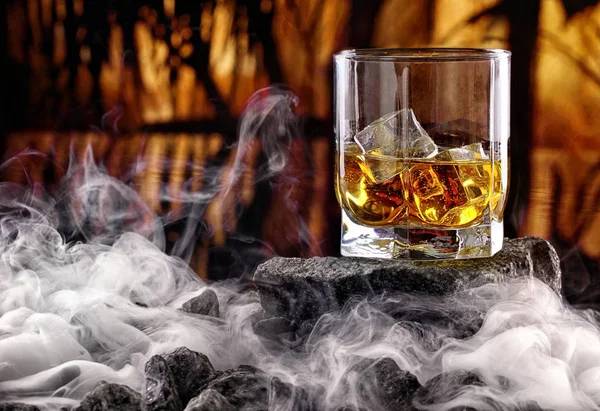 Glas whiskey en ijs. Creatieve foto glas whisky op steen met mist en zonsondergang achtergrond. Kopieer ruimte. Schot reclame — Stockfoto