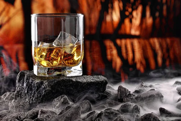 Glas whiskey en ijs. Creatieve foto glas whisky op steen met mist en zonsondergang achtergrond. Kopieer ruimte. Schot reclame — Stockfoto