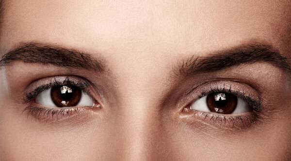 Крупным планом с красивым женским карим глазом. Чистая кожа, модный натуральный макияж. Хорошее зрение
