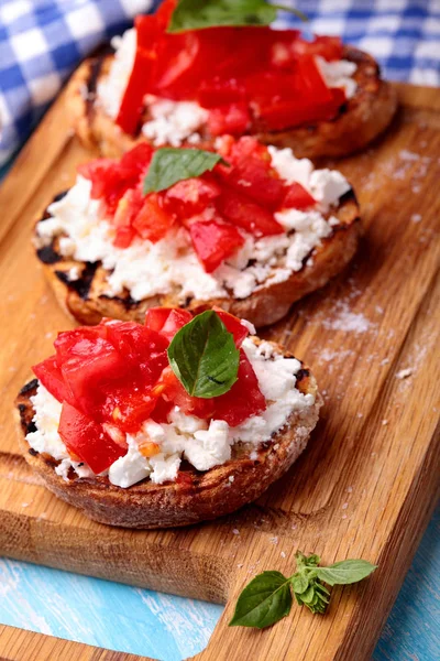 Domates, beyaz peynir, fesleğen, dereotu ve baharat ve olivia ile lezzetli bruschetta ahşap tahta üzerinde petrol. Seçici odak