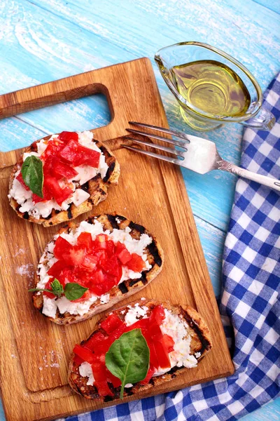 Domates, beyaz peynir, fesleğen, dereotu ve baharat ve olivia ile lezzetli bruschetta ahşap tahta üzerinde petrol. Seçici odak