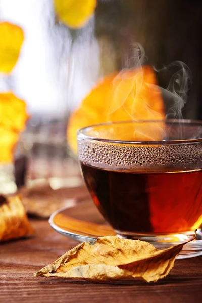 Ahşap pencere pervazına sarı atumn ile üzerinde çay yaprakları. Ufuk yağmurlu pencere ve srcond planı üzerinde sonbahar ağaçlar. Tea.Selective odak. Sonbahar kavramı. Sıcak içecekler