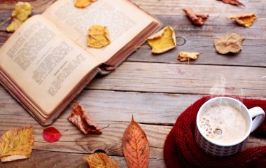 Fincan sıcak cappuccino kahve ahşap tablo sonbahar yaprakları, kitap. Sonbahar ruh kavramı. Sıcak Sonbahar resim. Seçici odak. Space.top görünüm Kopyala