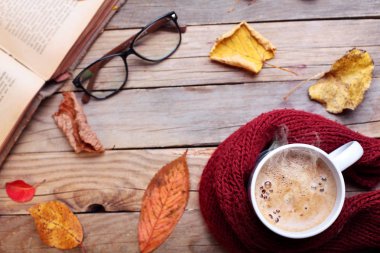 Fincan sıcak cappuccino kahve sonbahar yaprakları, kitap ve gözlük ile ahşap masa üzerinde. Sonbahar kavramı. Sıcak Sonbahar resim. Seçici odak. Üstten Görünüm