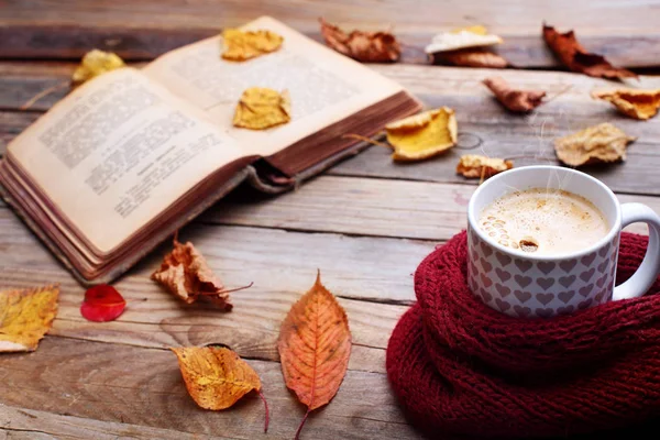 Copa de café capuchino caliente en la mesa de madera con hojas de otoño, book.Autumn concept.Warm otoño foto. —  Fotos de Stock