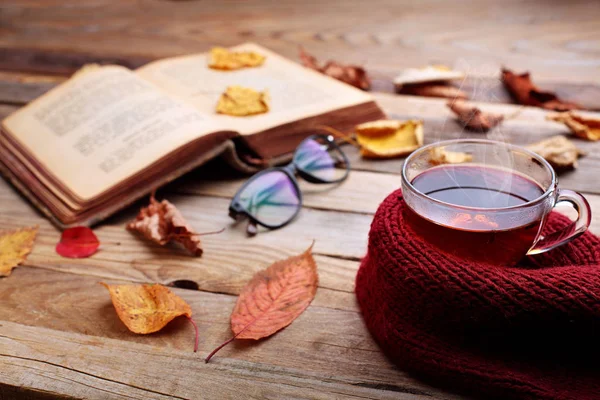 Taza de té caliente en la mesa de madera.Libro abierto yhojas rojas de otoño.Concepto de humor de otoño . —  Fotos de Stock