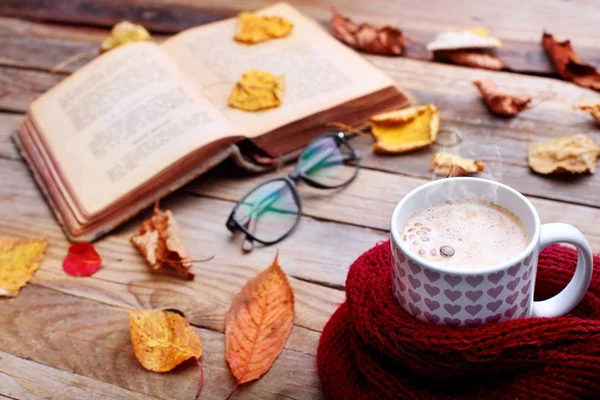 Copa de café capuchino caliente en mesa de madera con hojas de otoño, libro y gafas. Concepto de humor otoñal. Imagen cálida de otoño. Enfoque selectivo —  Fotos de Stock