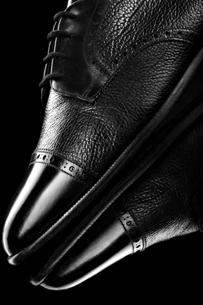 Siyah oxford ayakkabı siyah ayna arka plan cilalı. Ayakkabı Parlatıcı. Yakın çekim.