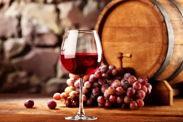 Kırmızı şarap. Bardak kırmızı şarap, üzüm ve varil ile natürmort. Seçici odak. Kopya alanı