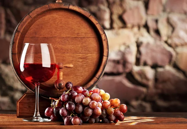 Kırmızı şarap. Bardak kırmızı şarap, üzüm ve varil ile natürmort. Seçici odak. Kopya alanı