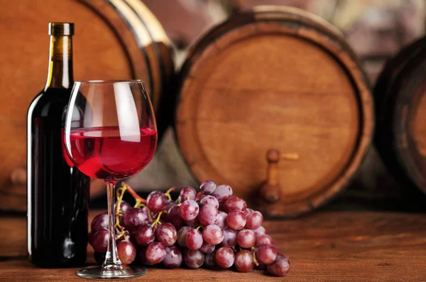 Kırmızı şarap. Cam ve şişe kırmızı şarap, üzüm ve varil ile natürmort. Seçici odak. Şarap mahzeni atmosfer. Kopya alanı
