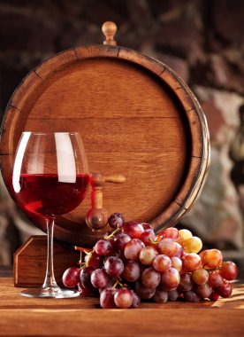 Kırmızı şarap. Bardak kırmızı şarap, üzüm ve varil ile natürmort. Seçici odak. Kopya alanı