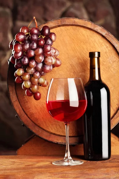 Vino tinto. Vida útil con copa y botella de vino tinto, uvas y barrica. Enfoque selectivo. Ambiente bodega . — Foto de Stock