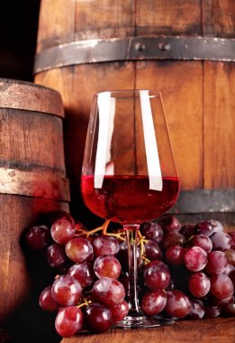Kırmızı şarap. Bardak kırmızı şarap, üzüm ve varil ile natürmort. Seçici odak. Şarap mahzeni atmosfer. Kopya alanı