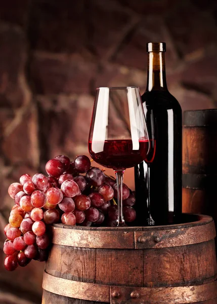 赤ワイン。ガラスと赤ワイン、ぶどうと樽の瓶のある静物。選択と集中。ワインセラーの雰囲気。コピー スペース — ストック写真
