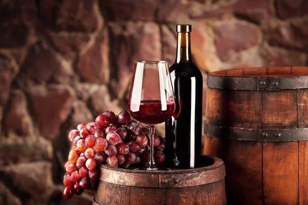 Czerwone wino. Martwa natura z szkła i butelkę czerwonego wina, winogrona i beczki. Selektywny fokus. Winiarnia atmosferę. Miejsce — Zdjęcie stockowe