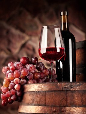 Kırmızı şarap. Cam ve şişe kırmızı şarap, üzüm ve varil ile natürmort. Seçici odak. Şarap mahzeni atmosfer. Kopya alanı