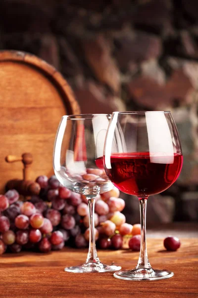 Kırmızı şarap. İki kadeh kırmızı şarap, üzüm ve namlu dolu ve boş ile natürmort. Seçici odak. Kopya alanı