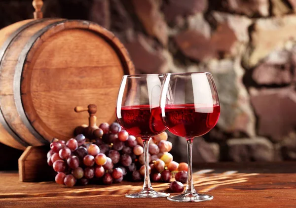 Kırmızı şarap. İki kadeh kırmızı şarap, üzüm ve varil ile natürmort. Seçici odak. Kopya alanı