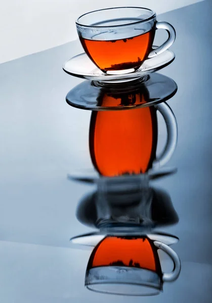 Taza de té con plato en la superficie reflectante.Reflexión creativa.Fondo degradado —  Fotos de Stock