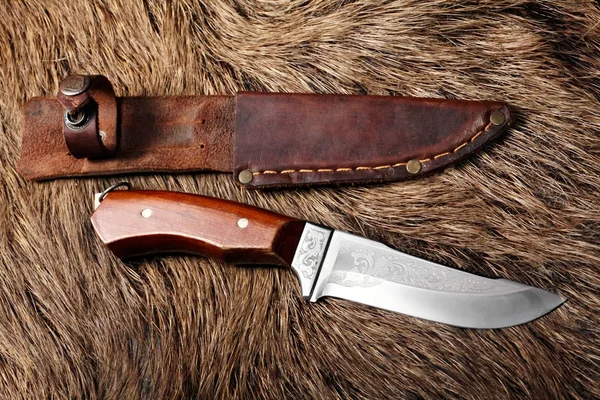 hunting knife with leather sheath on a wild boar furs background